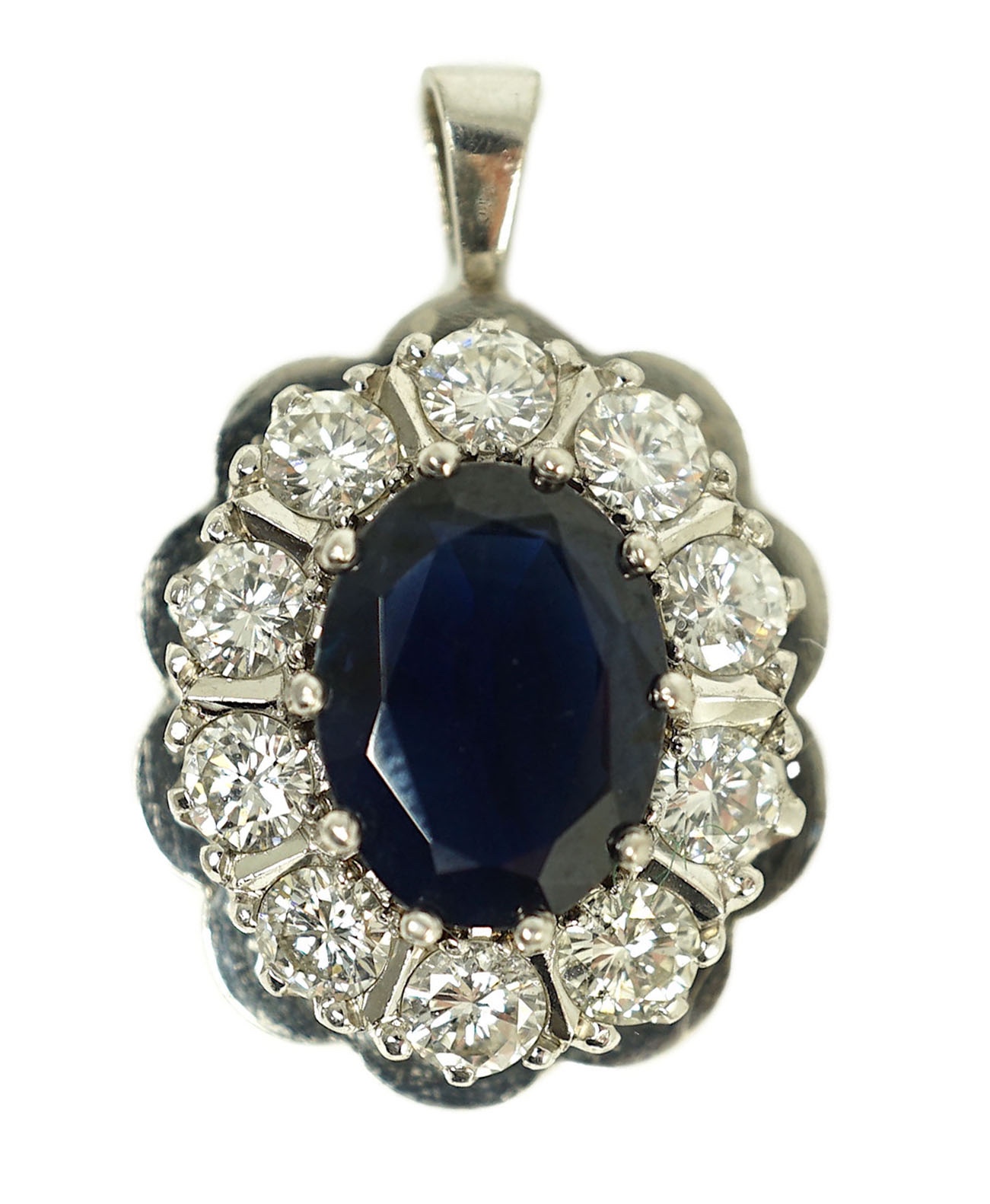 A modern 18ct white gold, sapphire and diamond set oval cluster pendant